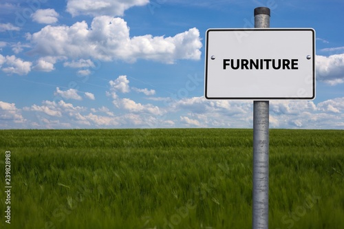 white road sign. the word FURNITURE is displayed. The sign stands on a field with blue background