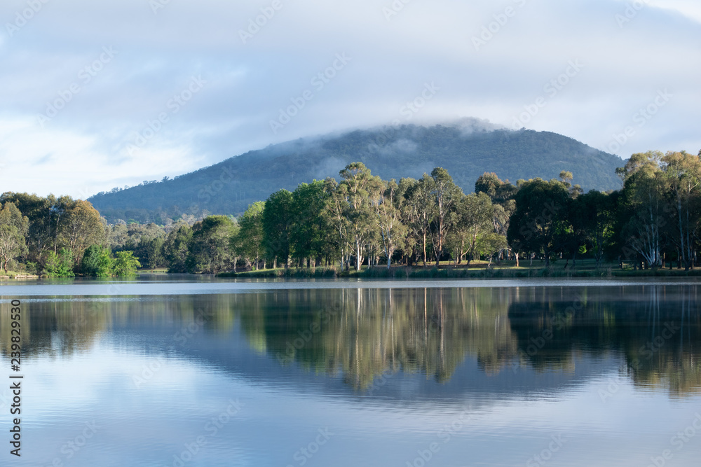 Fototapeta premium Reflection of hill and trees in Tuggeranong Lake