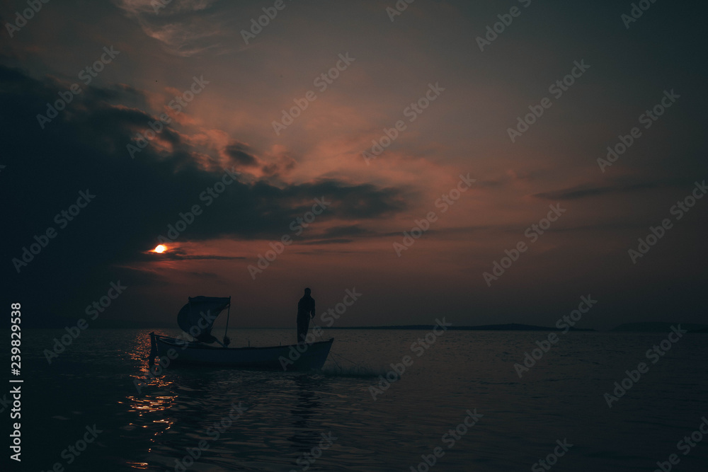 Fototapeta premium A fisherman tries to catch fish in sunset
