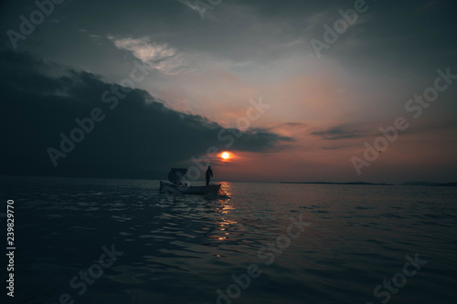 A fisherman tries to catch fish in sunset