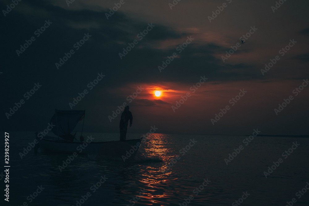 Fisherman tries to collect fishes in sunset