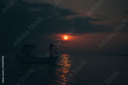 Fisherman tries to collect fishes in sunset