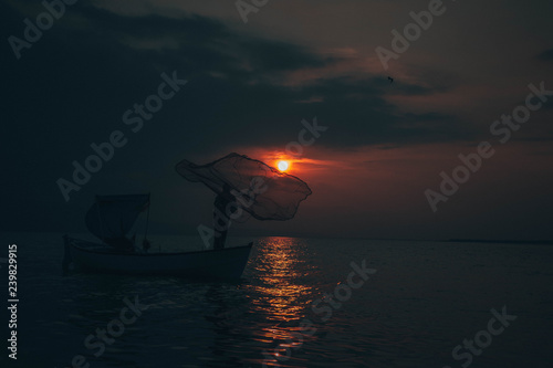 Fisherman tries to collect fishes in sunset