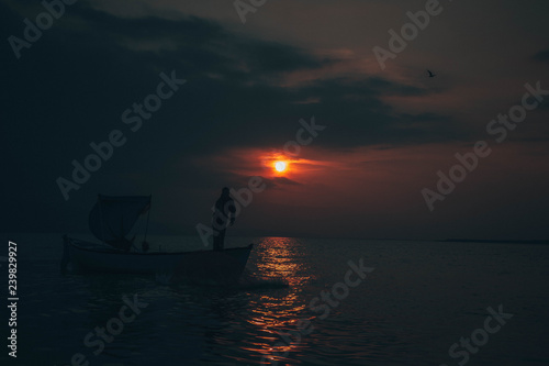 Fisherman tries to collect fishes in sunset