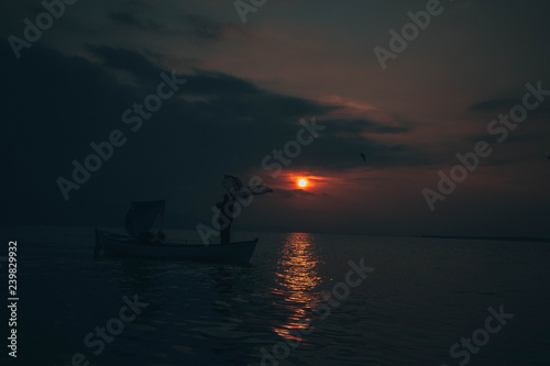 Fisherman tries to collect fishes in sunset