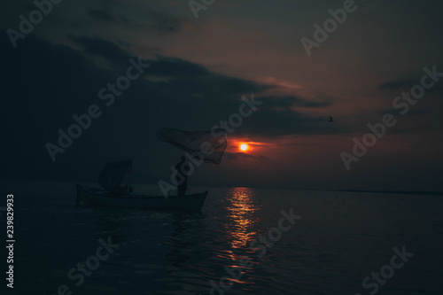 Fisherman tries to collect fishes in sunset