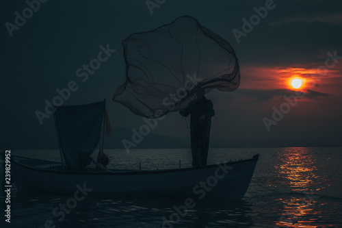 Fisherman tries to collect fishes in sunset