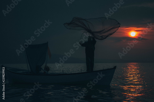 Fisherman tries to collect fishes in sunset
