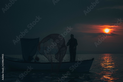 Fisherman tries to collect fishes in sunset