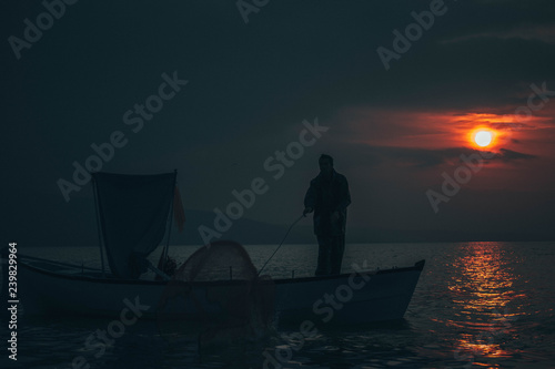 Fisherman tries to collect fishes in sunset