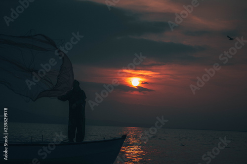 Fisherman tries to collect fishes in sunset