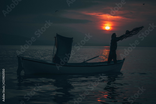 Sun goes down while fisherman throws his fishnet to collect fishes