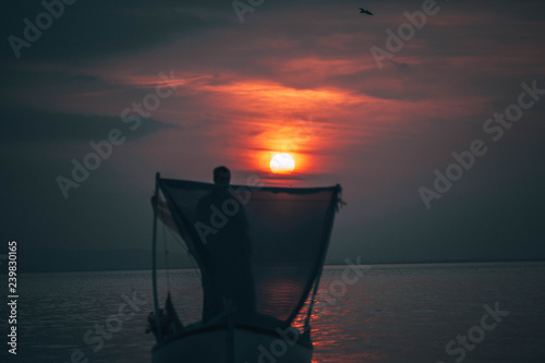 Sun goes down while fisherman throws his fishnet to collect fishes