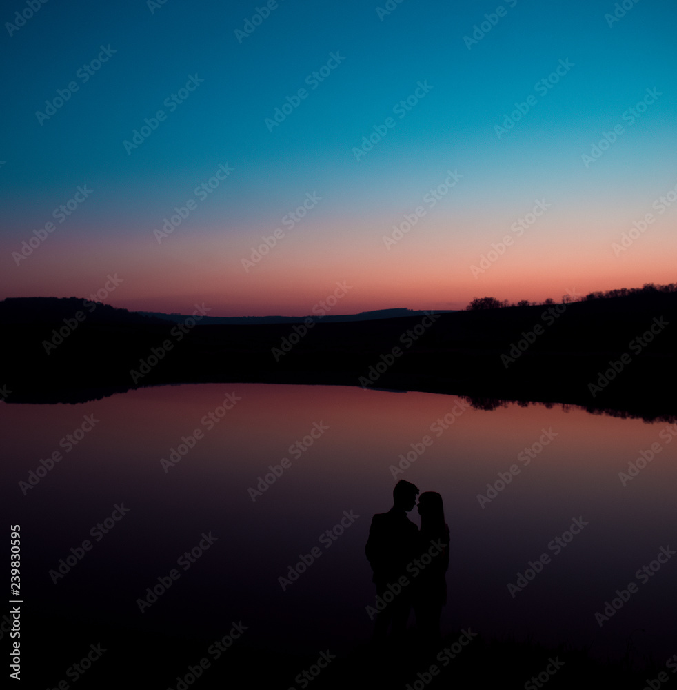 Silhouette of young couple on background of sunset.