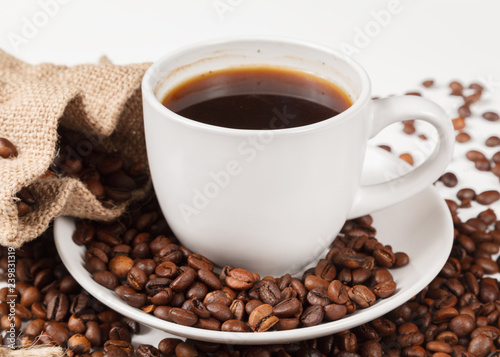 A Cup of strong coffee and a textile bag in roasted coffee beans, on a white background, isolated