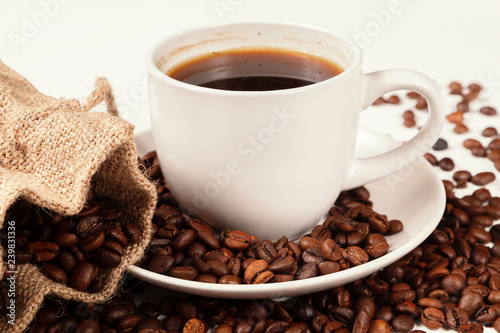 A Cup of strong coffee and a textile bag in roasted coffee beans, on a white background, isolated