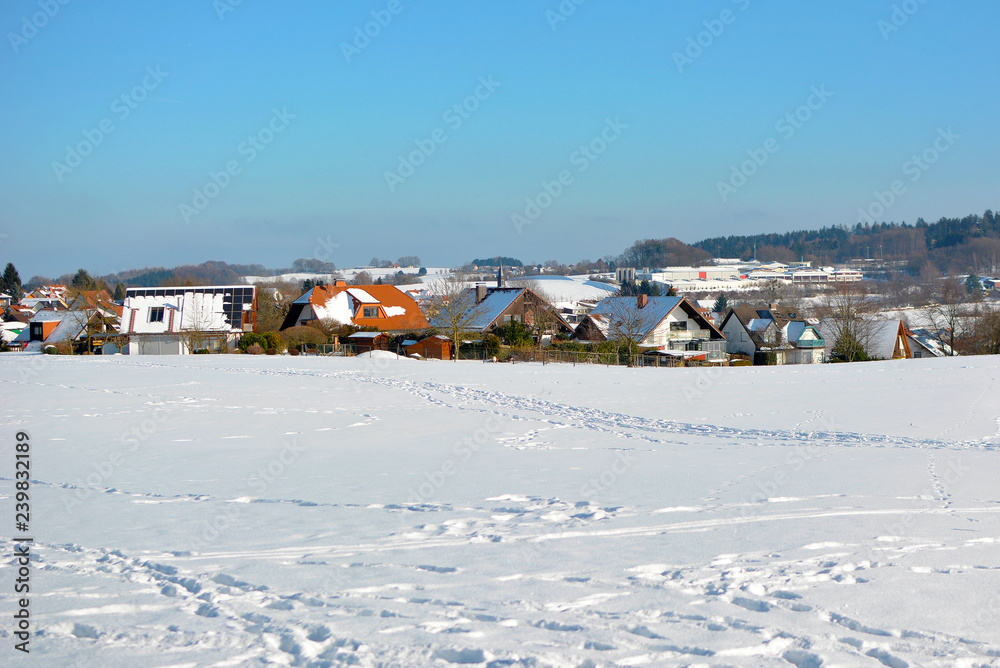 View of small rural town in Odenwald in Germany with clearing covered in snow during winter View of small rural town in Odenwald in Germany with clearing covered in snow during winter