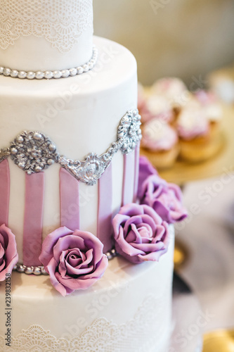 Candy bar table set. Cookies, eclairs, macaroons, fruits, cream and layered cakes. Pastel violet colours.