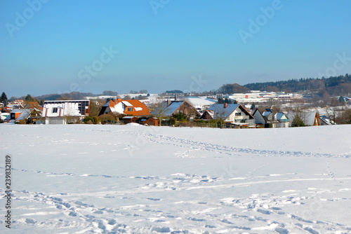 View of small rural town in Odenwald in Germany with clearing covered in snow during winter