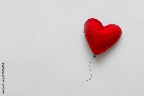 Valentines day card. Red felt heart shape balloon on thread. Minimalist concept