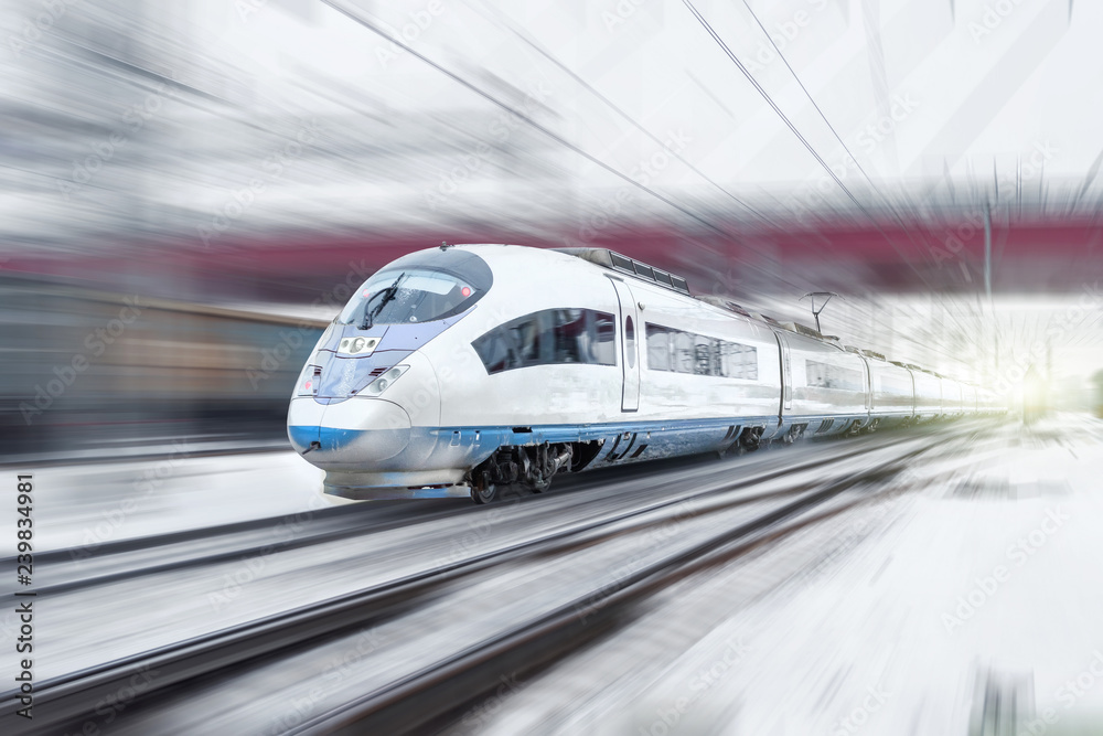 Obraz premium Pociąg jedzie z dużą prędkością w zimie wokół śnieżnego krajobrazu przemysłowego miasta