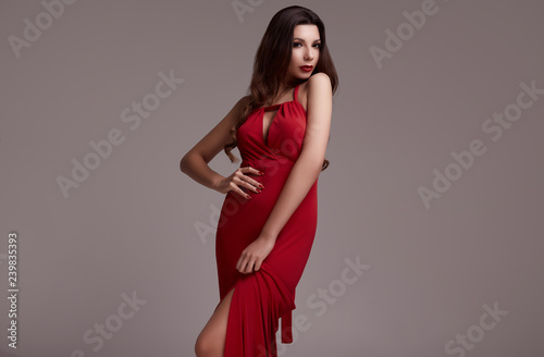 Gorgeous young brunette woman with curly hair in red dress