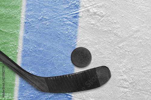 Hockey stick, puck and fragment of the ice arena with green and blue lines