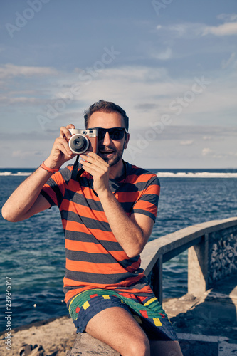 Man using vintage film camera on a ocean / sea vacation. © astrosystem
