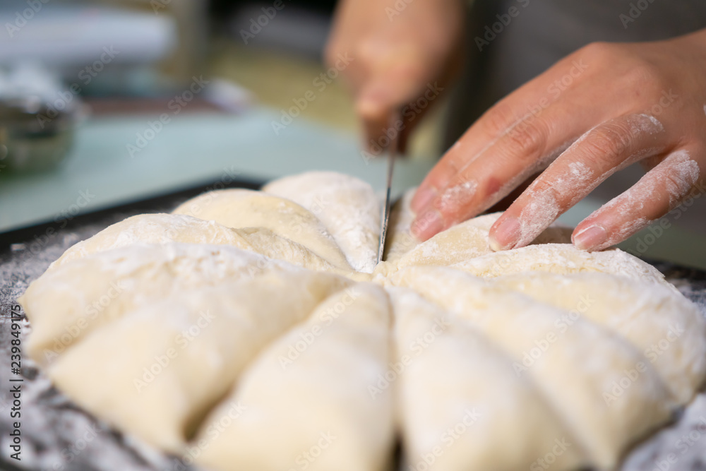 Cutting raw dough in flour with a knife (close-up of hands cutting dough)