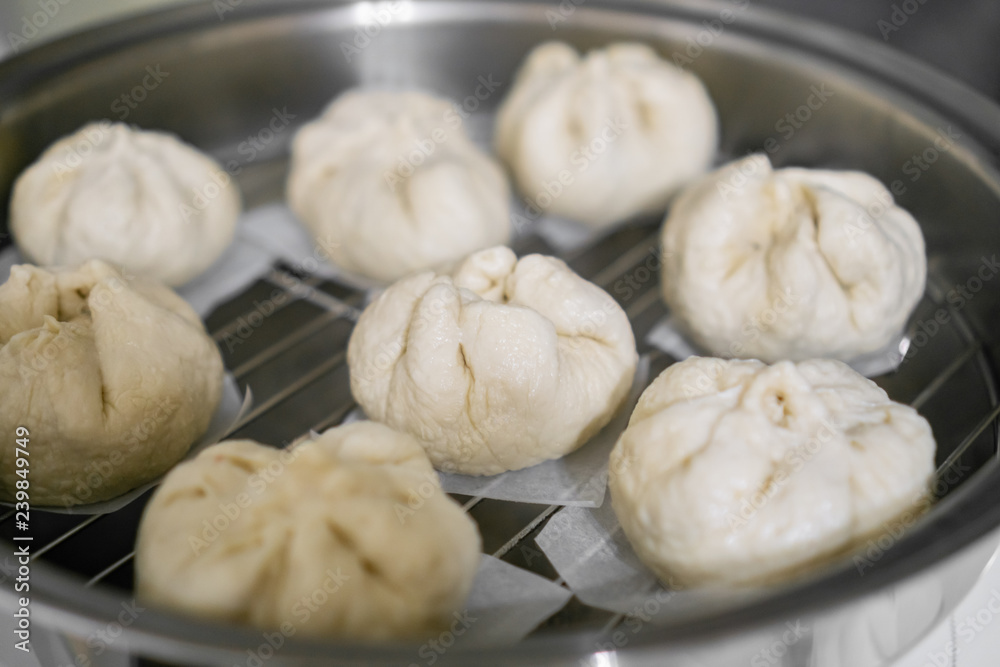 Chinese dumplings (buns) being steamed on a modern stainless steel wok pan Chinese dumplings (buns) being steamed on a modern stainless steel wok pan