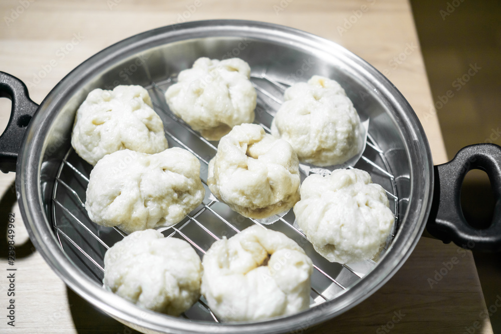 Chinese dumplings (buns) being steamed on a modern stainless steel wok pan Chinese dumplings (buns) being steamed on a modern stainless steel wok pan