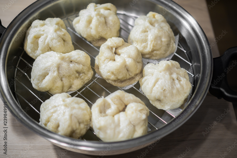 Chinese dumplings (buns) being steamed on a modern stainless steel wok pan Chinese dumplings (buns) being steamed on a modern stainless steel wok pan