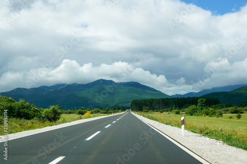 Driving on an empty road towards the mountains. Road trip on a summer day in Croatia. 