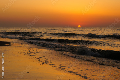 Fototapeta Naklejka Na Ścianę i Meble -  Sunrise with a beautiful orange sun rising from the Black Sea waves. Empty beach landscape.