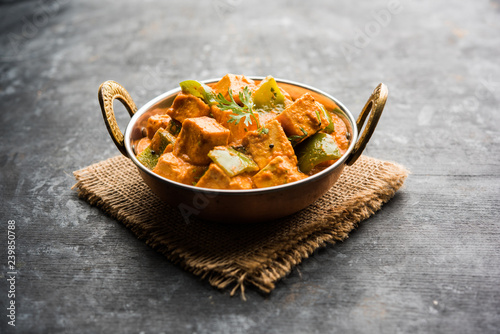 Malai or achari Paneer in a gravy made using red gravy and green capsicum. served in a bowl. selective focus photo