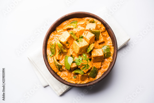 Malai or achari Paneer in a gravy made using red gravy and green capsicum. served in a bowl. selective focus