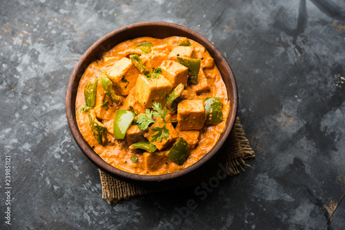 Malai or achari Paneer in a gravy made using red gravy and green capsicum. served in a bowl. selective focus