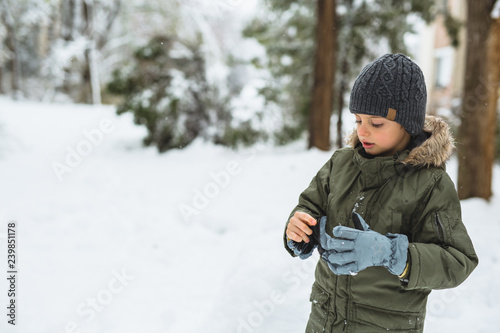 cute little boy putting winter glows outdoor