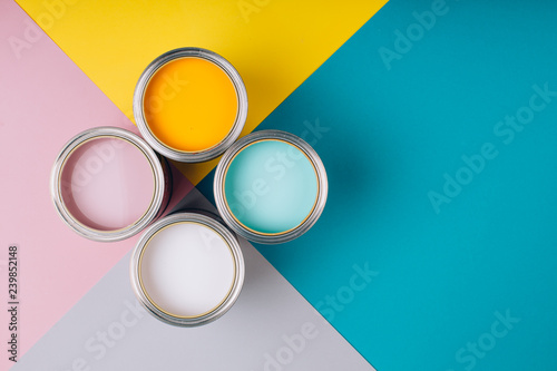 Four open cans of paint on bright symmetry background. Yellow, white, pink, turquoise colors of paint. Place for text. Renovation concept.