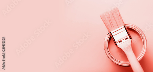 Fototapeta Naklejka Na Ścianę i Meble -  Brush with wooden handle on open can with Coral paint on pastel background. Renovation concept. Macro.