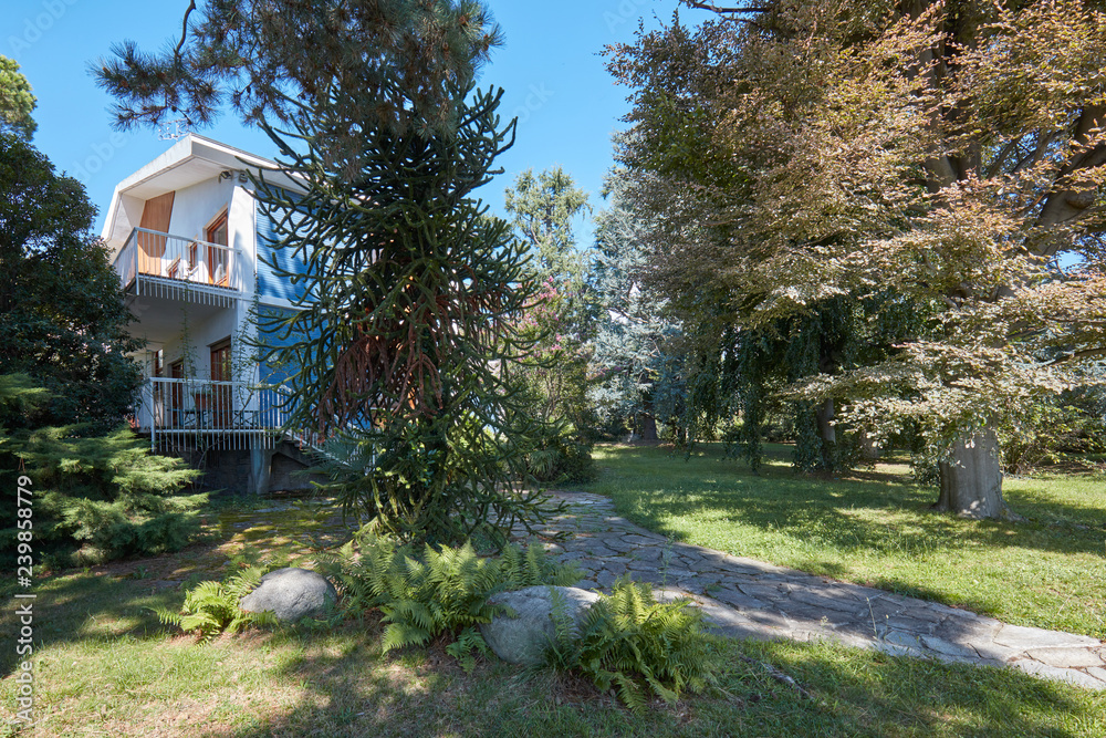 Villa with garden and stone tiled path in a sunny summer day, clear blue sky in Italy Villa with garden and stone tiled path in a sunny summer day, clear blue sky in Italy