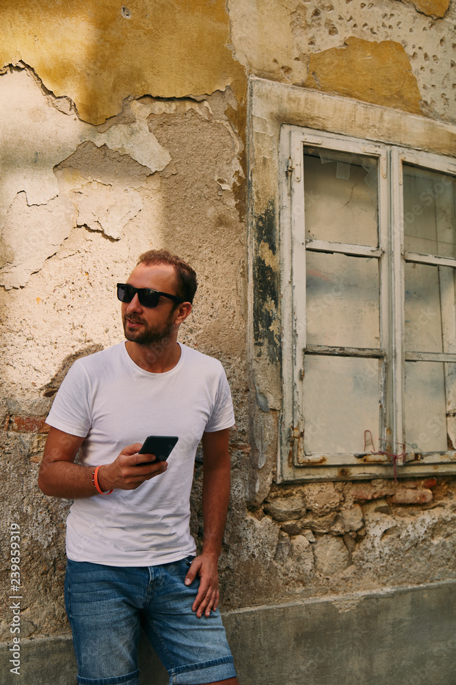 Modern guy using cellphone in the European city. Modern guy using cellphone in the European city.