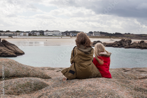 the sisters are sitting on the shore of the ocean