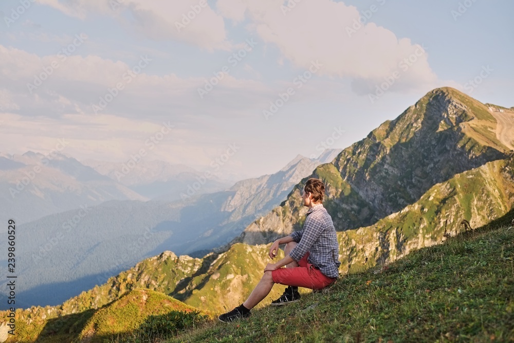 man sits on top of a mountain enjoying the view