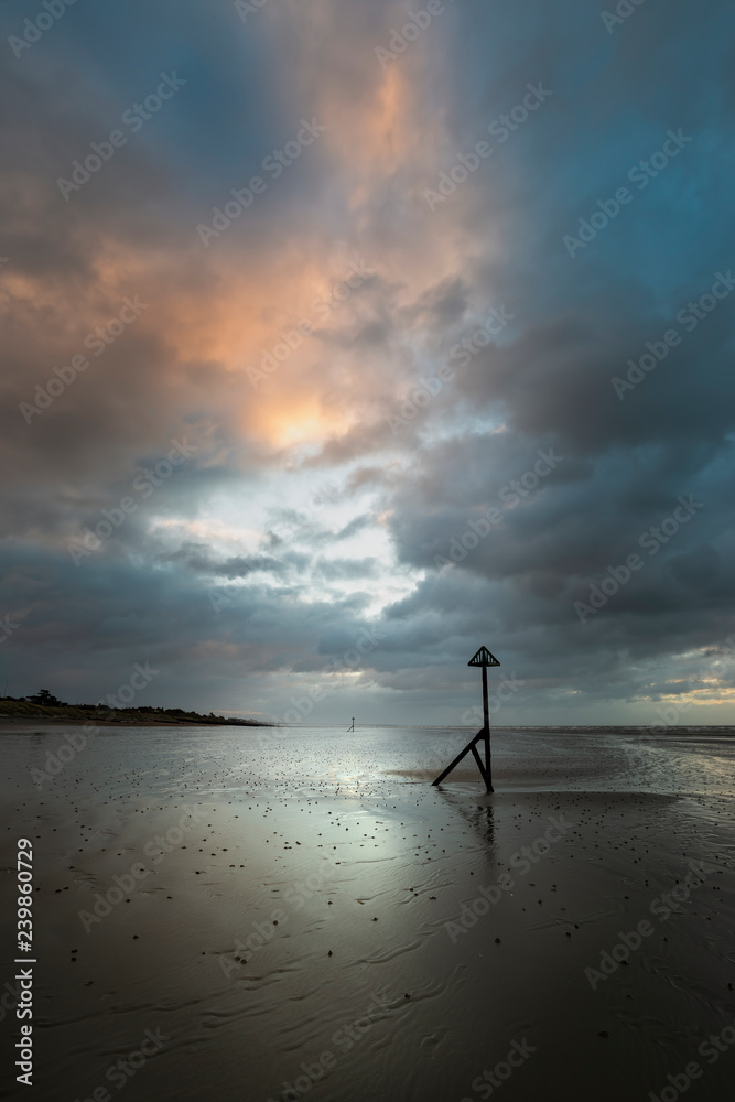 Stunning Winter sunrise over West Wittering beach in Sussex England with wind blowing sand across the beach