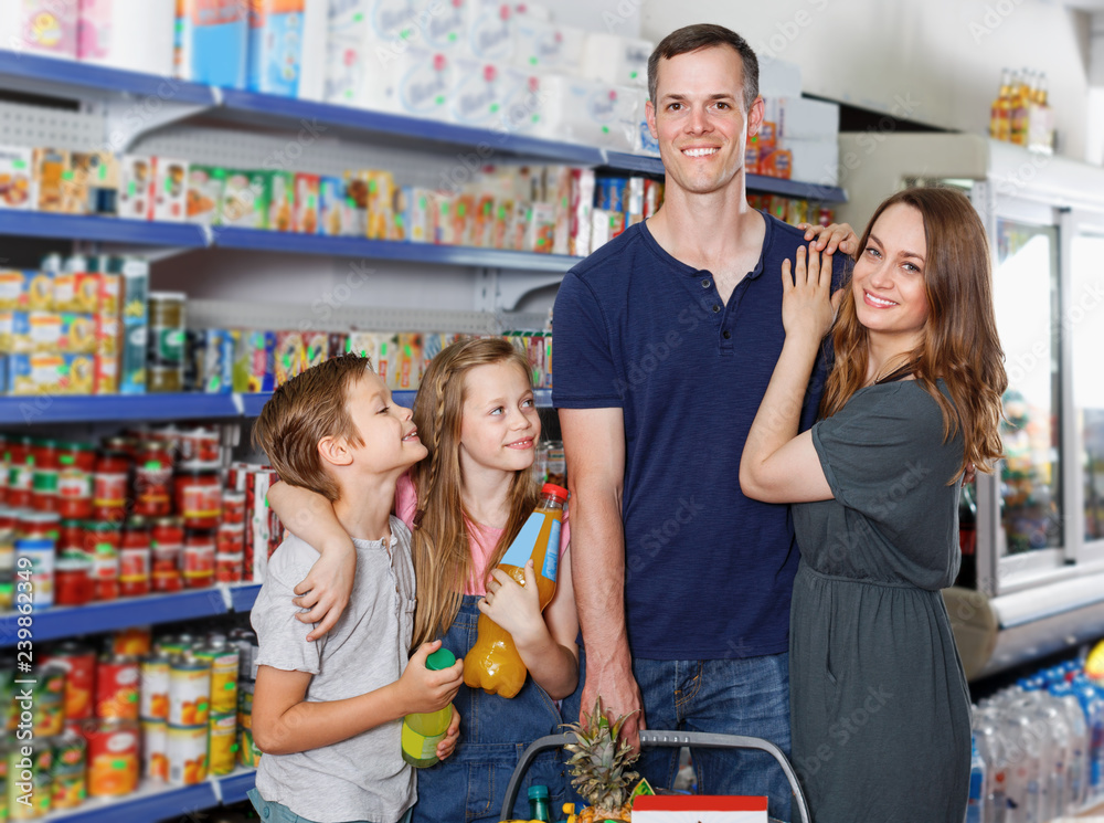 Family with two kids with cart of food  in local supermarket
