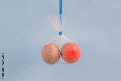 Testicular cancer concept: eggs in a tulle bag on a blue background one egg red
