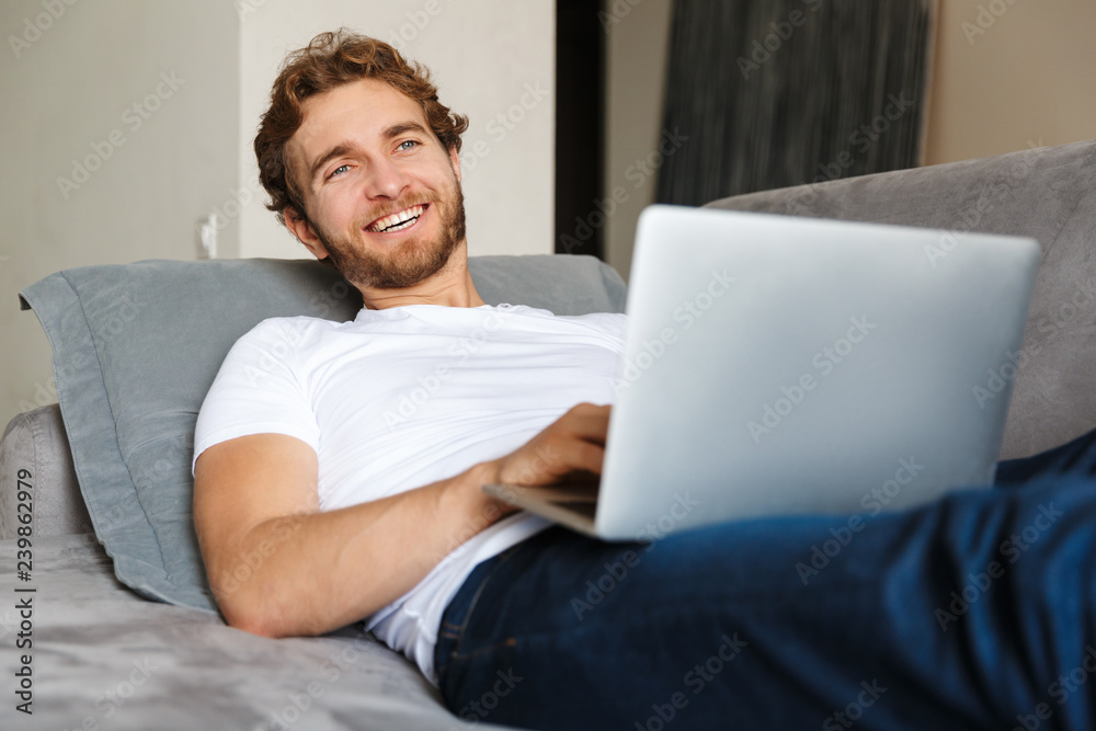 Handsome young bearded man on sofa at home using laptop computer. Handsome young bearded man on sofa at home using laptop computer.