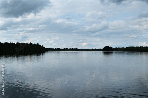 A beautiful lake landscape shot on an overcast cloudy day. Dark trees with a focus on the water and sky.