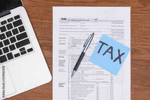 top view of tax form, laptop and blue card with 'tax' word on desk